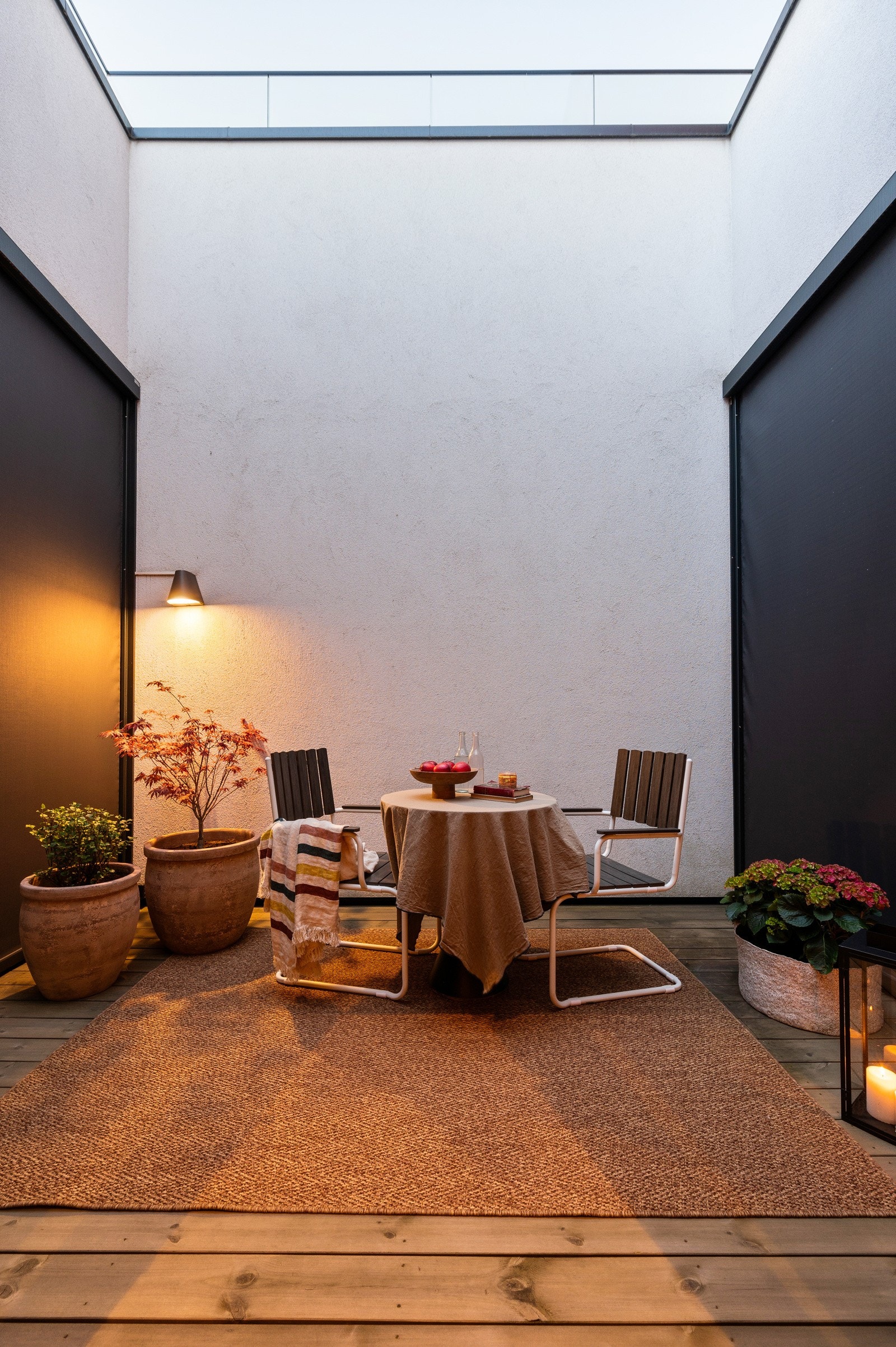 Gulvet er belagt med terrassebord i tre, og atriet er innredet med sittegruppe og dekorative plantekasser som skaper en lun atmosfære. Galleribilde