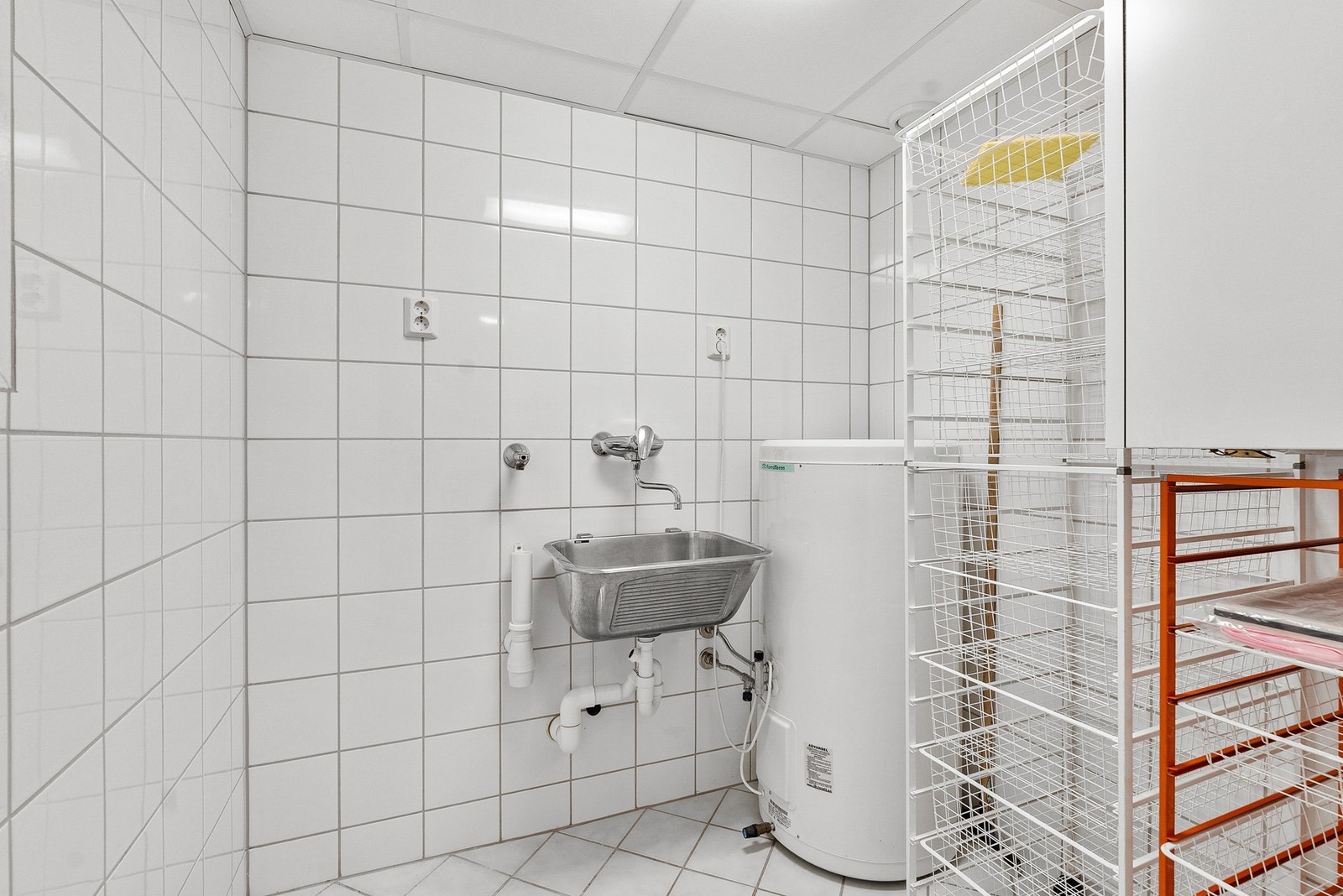 Flislagt vaskerom i tilknytnytning til badet, med varmekabler i gulvet. Vaskerommet har opplegg for vaskemaskin og skyllekar på veggen. Galleribilde