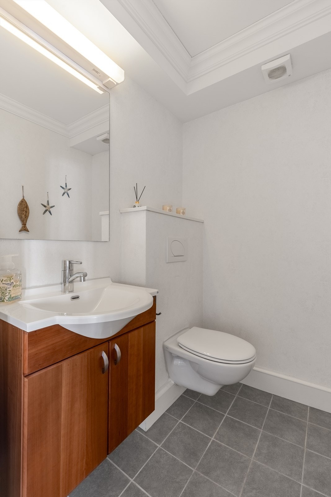 Praktisk toalettrom med vegghengt wc og servantinnredning Galleribilde