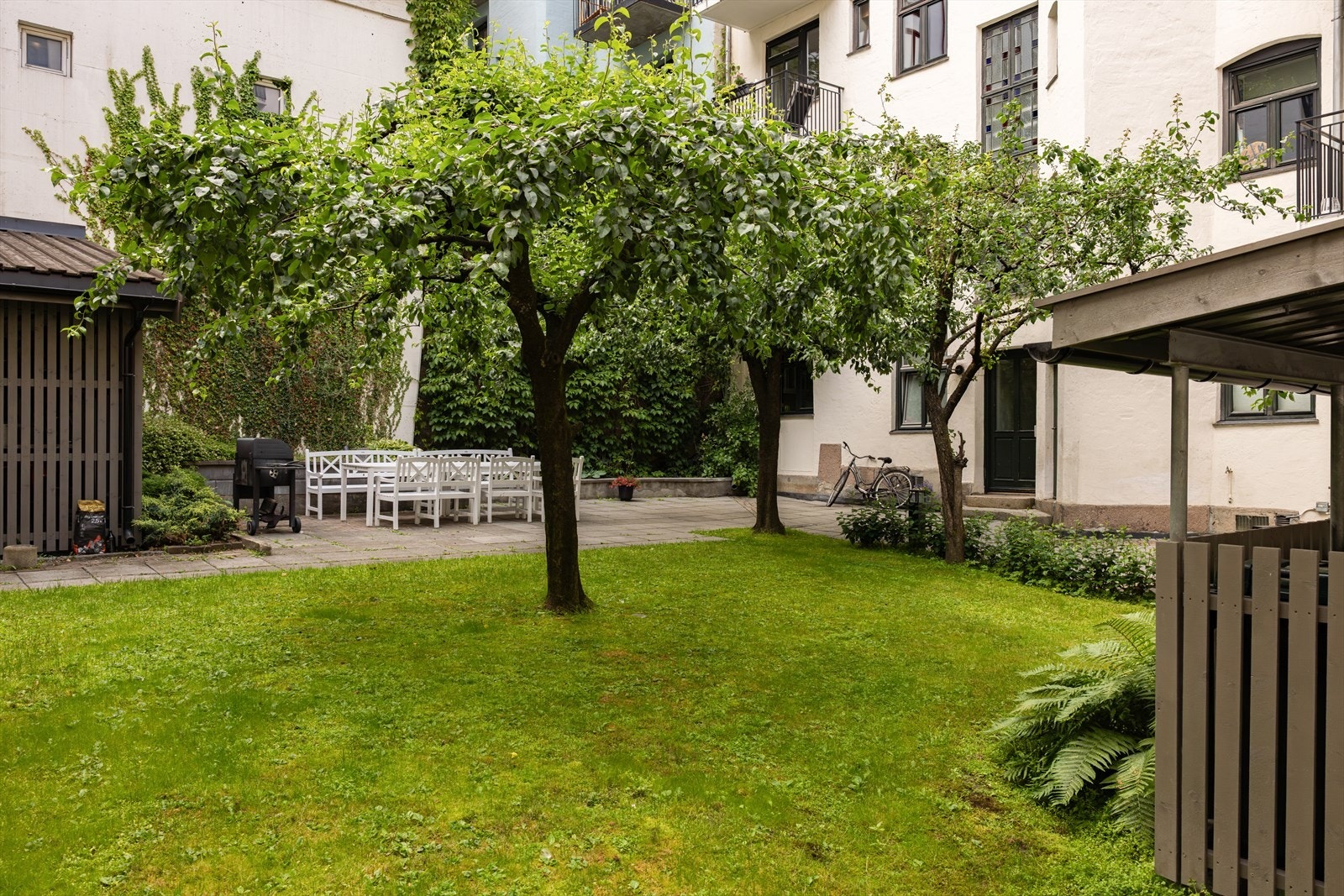 Trivelig opparbeidet bakgård med beplantning, sittegrupper og en felles grill Galleribilde