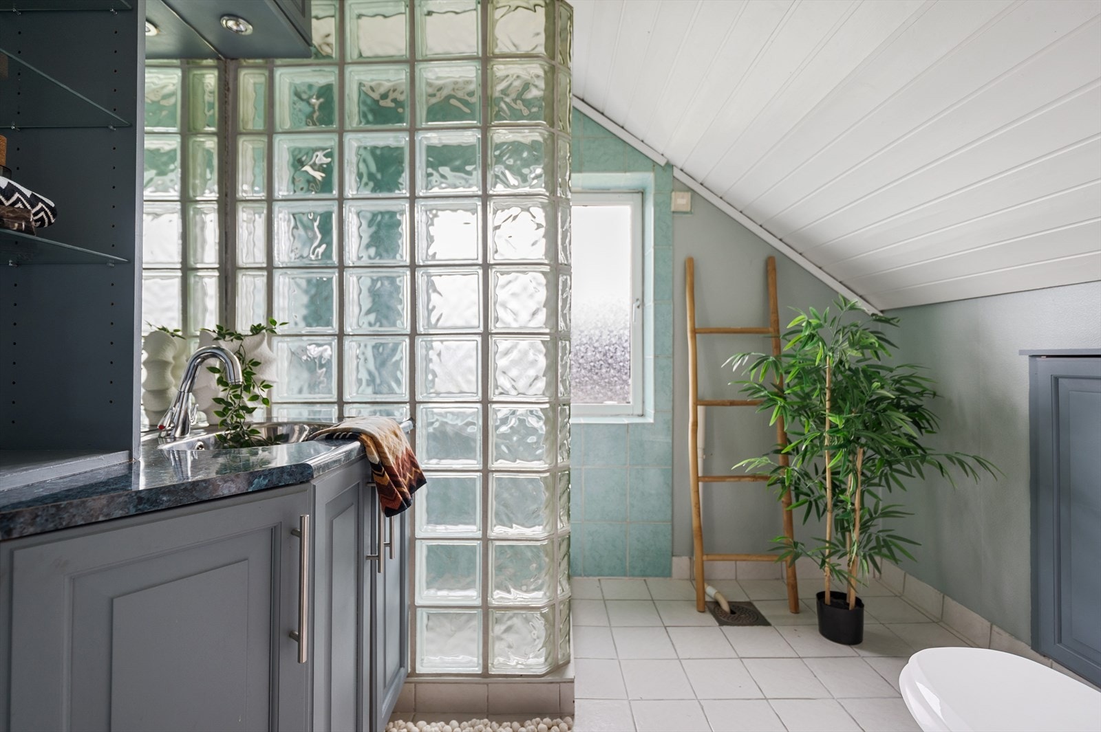 Karakteristisk bad med glassbyggestein, fliser på gulv og i dusjsonen, opplegg for vaskemaskin og kott bak knevegg. Galleribilde
