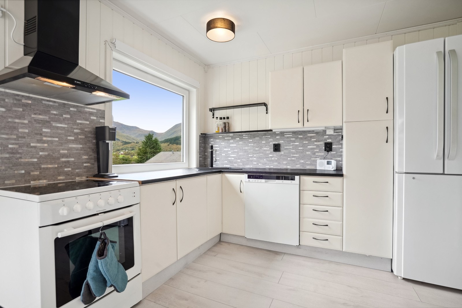 Innredning med lyse fronter og mørke håndtak. Benkeplate av laminat. Galleribilde