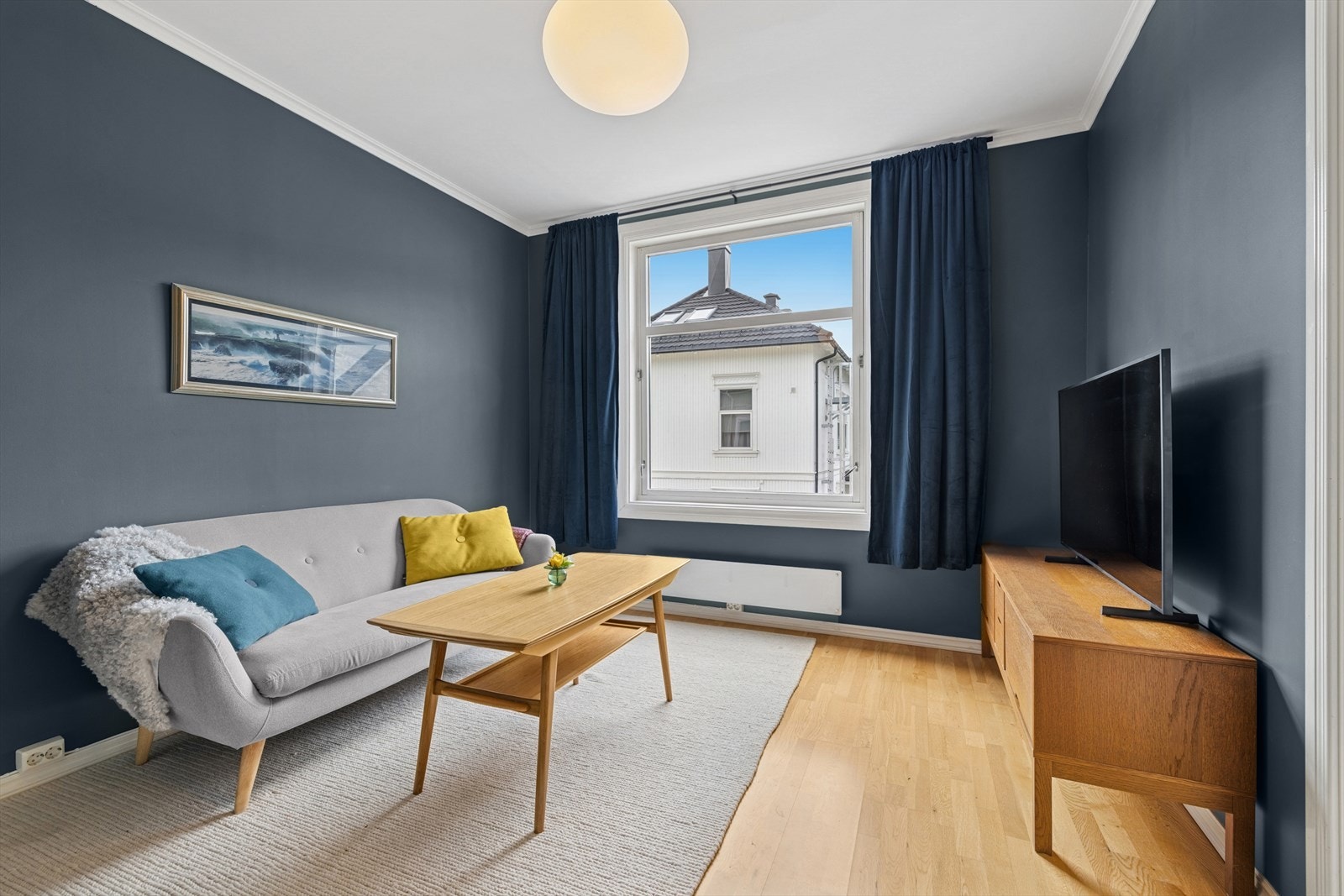 Stuen har et stilrent parkettgulv og malte flater i en elegant mørkeblå farge. Galleribilde