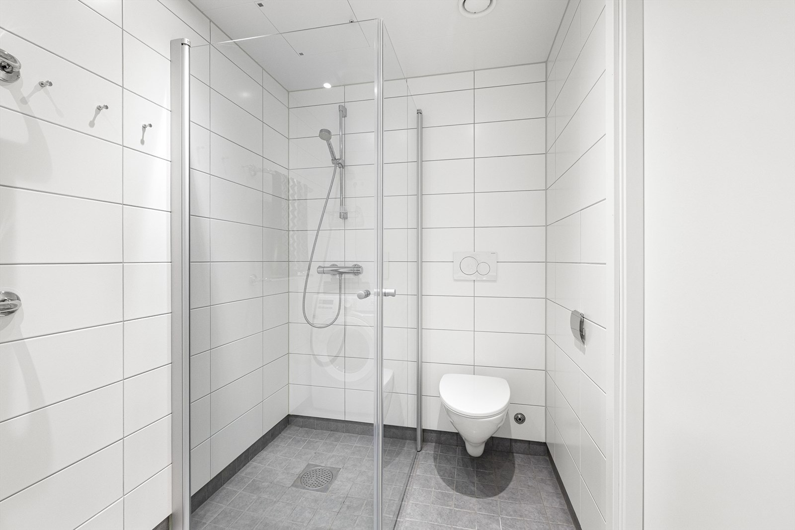 Badet er innredet med vegghengt klosett, servant nedfelt i innredningen, speilskap m/lys og dusjhjørne med svingbare glassdører. Det er opplegg for vaskemaskin. Galleribilde