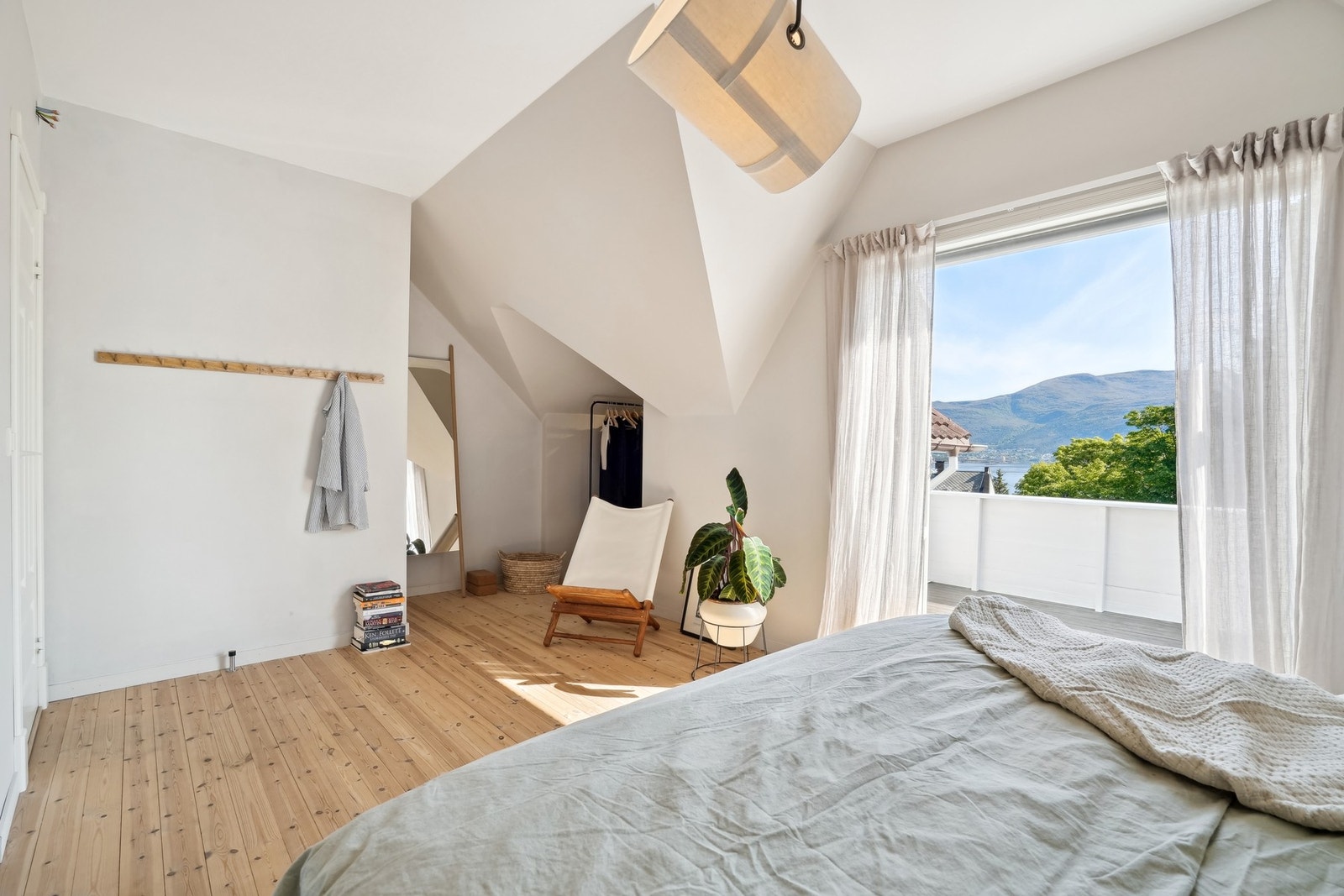 Et soverom som inviterer til hvile - med lune tekstiler, grønne planter og en stilren arkitektur. Galleribilde