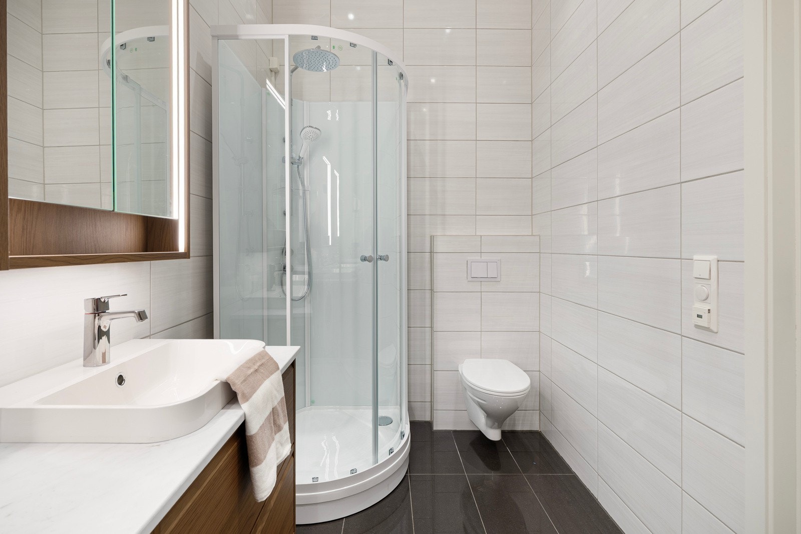 Videre er badet utstyrt med regnfallsdusj, vegghengt toalett, gulvvarme og innfelte downlights. Galleribilde