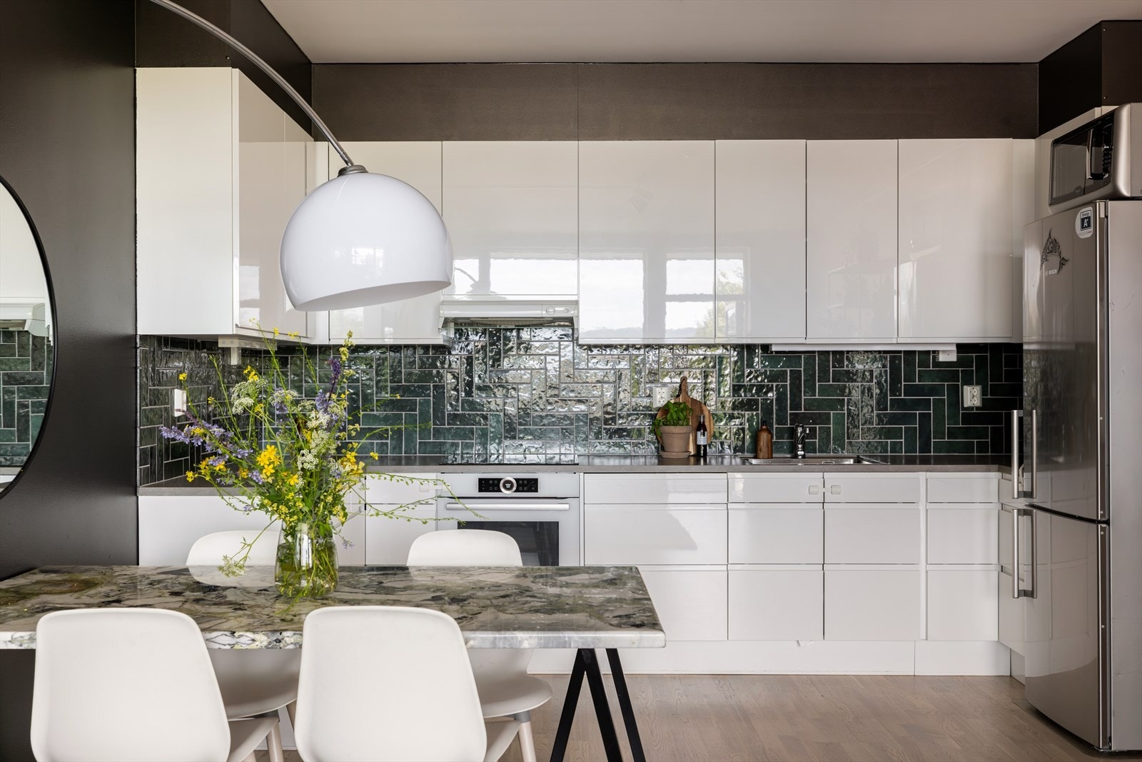 Lekkert kjøkken innredet med hvite, slette fronter, benkeplate i laminat og fliser på veggene Galleribilde