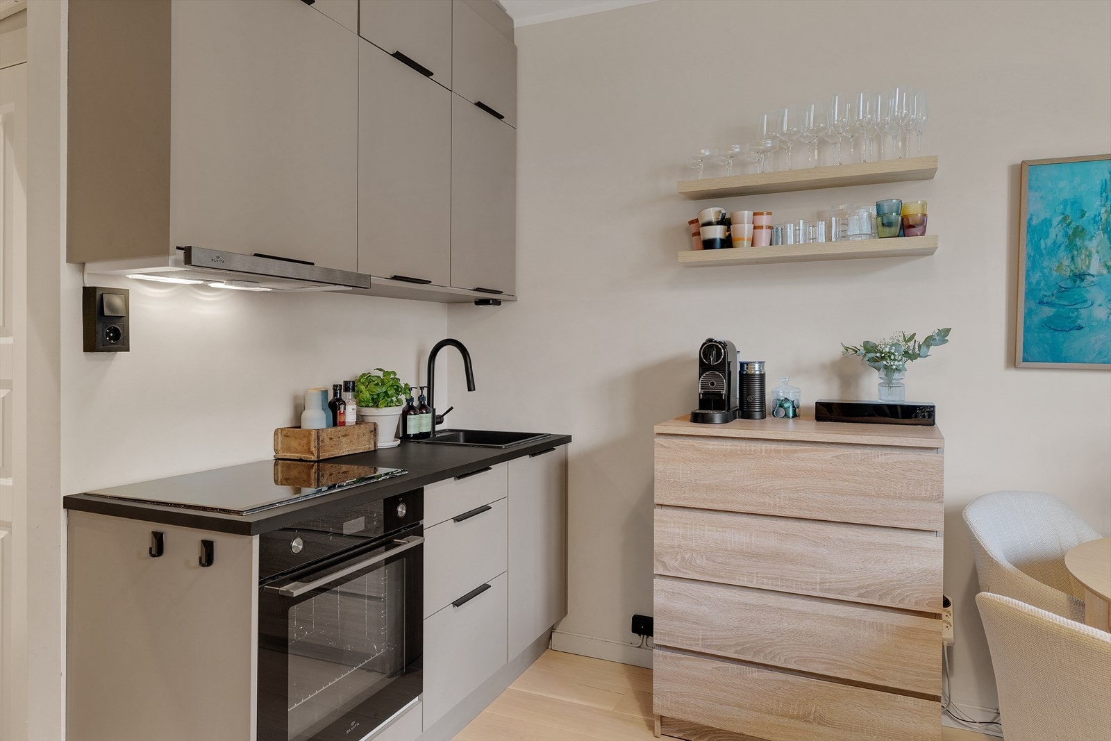 Benkeplaten i laminat har nedfelt vask, og kjøkkenet er utstyrt med integrert platetopp og stekeovn, samt kullfilterventilator over kokeplassen. Galleribilde