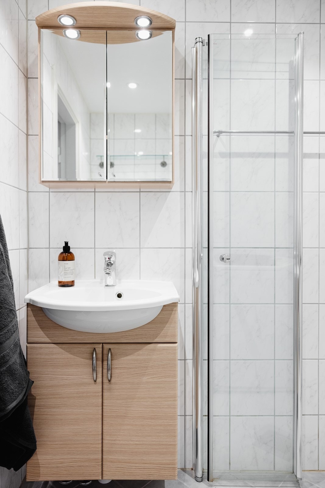 Badet er utstyrt med vegghengt toalett, servantinnredning med servant, ettgreps blandebatteri, blandebatteri/dusjarmatur og dusjdører i glass. Galleribilde