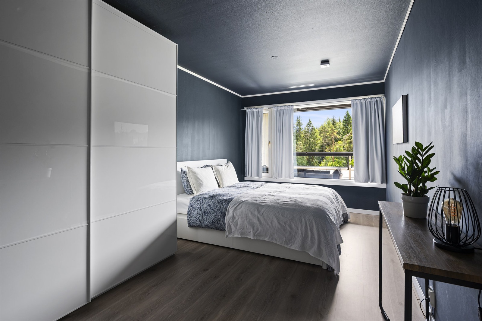 Et veldig stort soverom med nok av skapplass og plass til stor dobbeltseng med nattbord plassert på hver sin side Galleribilde