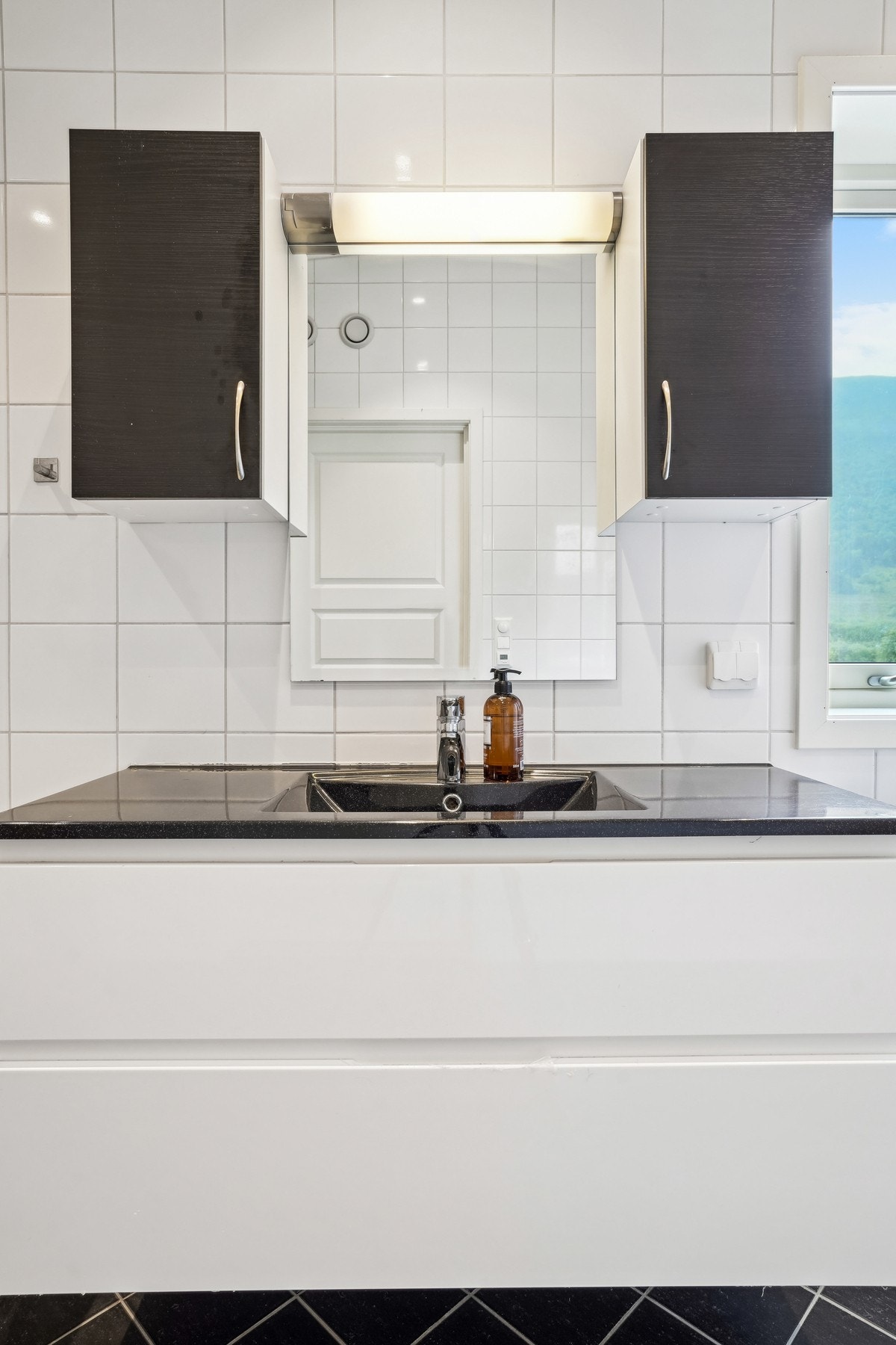 Et romslig baderomsmøbel med nedfelt servant og overliggende speil med belysning - det er godt med skap- og skuffeplass i innredningen. Galleribilde