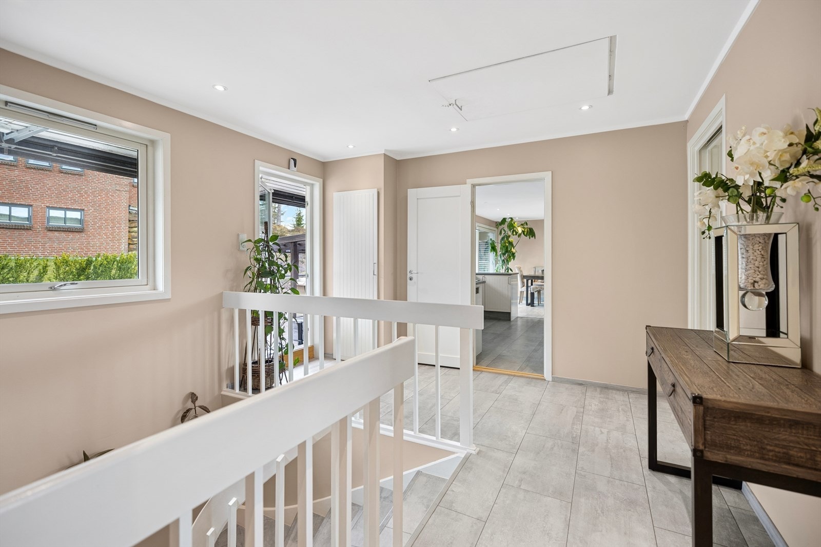 Opp trappen til første etasje blir du møtt av en lys gang som fører videre inn i boligens øvrige rom og markterrassen. Galleribilde