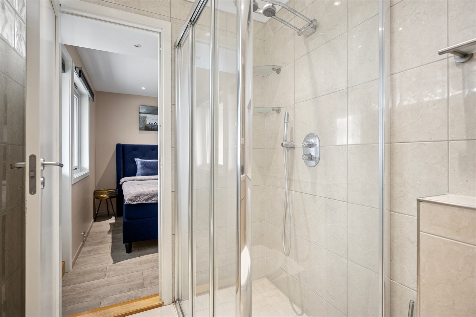 Badet har vegghengt toalett med skjult sisterne, håndklestang på veggen, dusjvegg og skyvedør i glass er også installert. Galleribilde