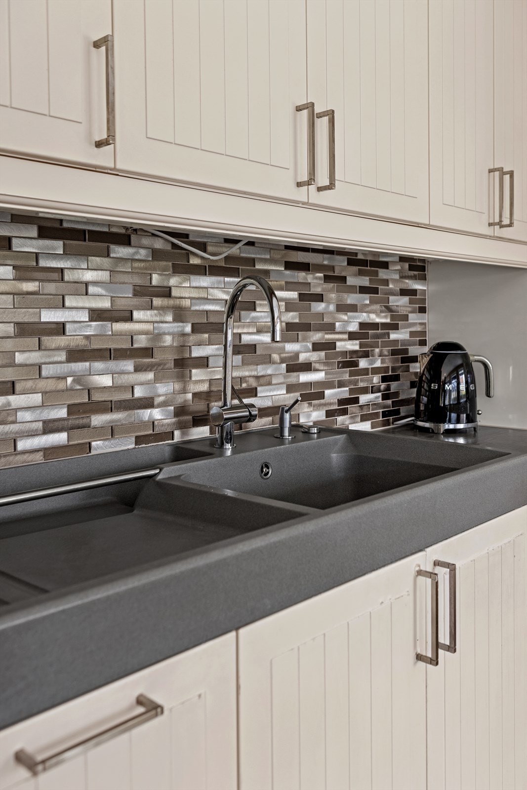 Kjøkkenet er utstyrt med integrert oppvaskmaskin, induksjonstopp, stekeovn og mikrobølgeovn, samt et side-by-side kjøleskap med fryseskap og vanntilkobling Galleribilde