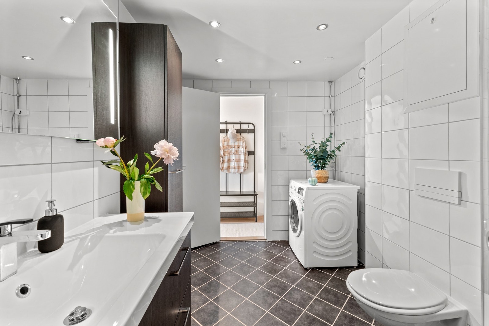 Flisvalget på badet er tidløst i hvite, avlange veggfliser og sorte rutede gulvfliser. Galleribilde