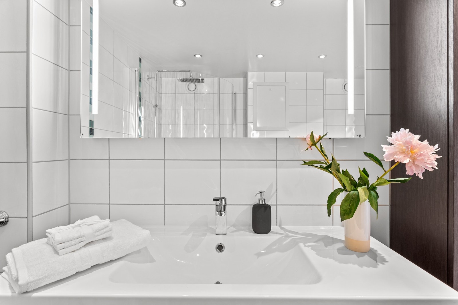 Samt servantskap med heldekkende servant, speil med lysarmatur på vegg og vegg hengt klosett. Galleribilde