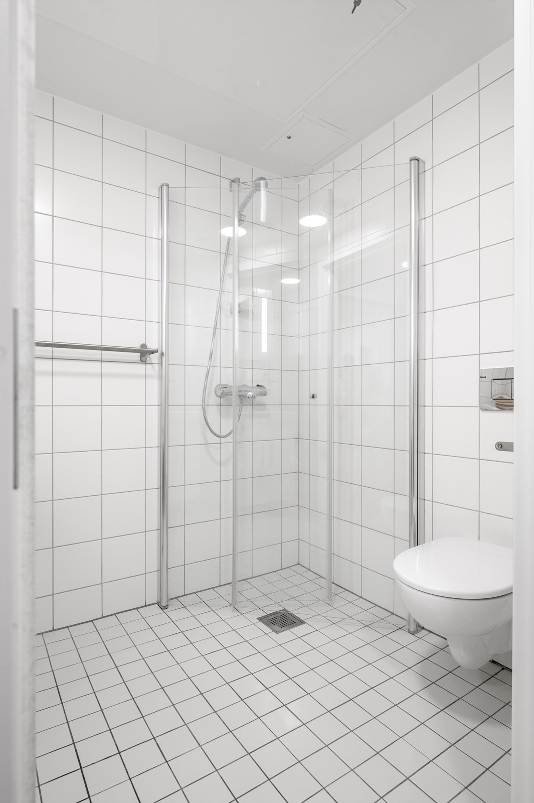 Videre har badet vegghengt toalett med innebygget sisterne og dusjhjørne med innfellbare glassdører og hånddusj. Galleribilde