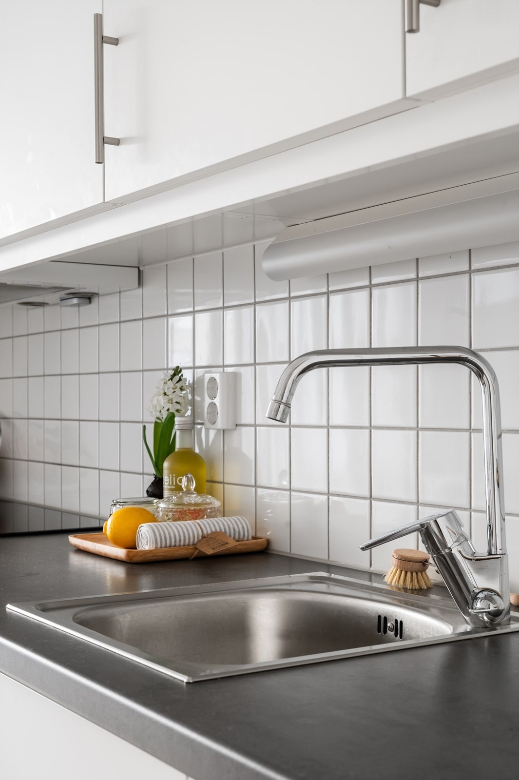 Kjøkkeninnredningen er av hvite, glatte fronter og benkeplate i laminat med nedfelt oppvaskkum i rustfritt stål Galleribilde