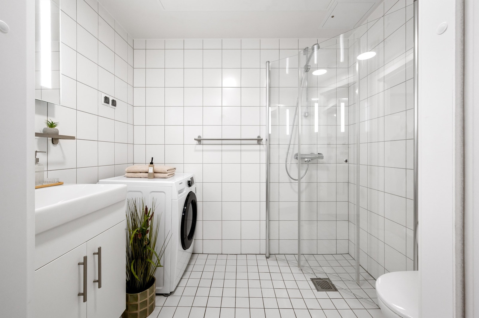 Badet er pent flislagt på gulv og vegger med vannbåren varme i gulvet. Det er opplegg og plass for vaskemaskin og tørketrommel. Galleribilde