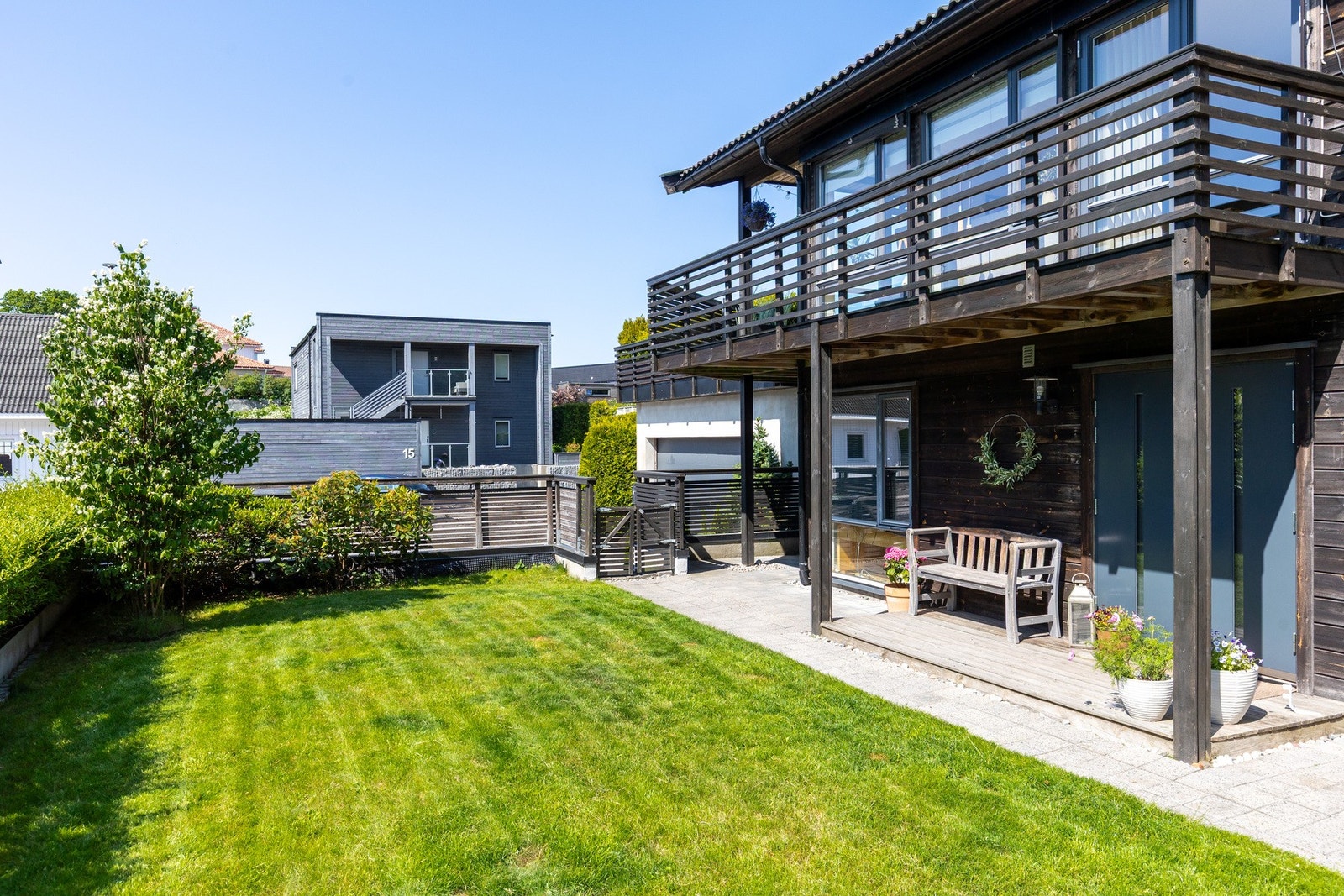 Fin uteplass utenfor boligen med gressplen hvor de minste kan leke trygt Galleribilde