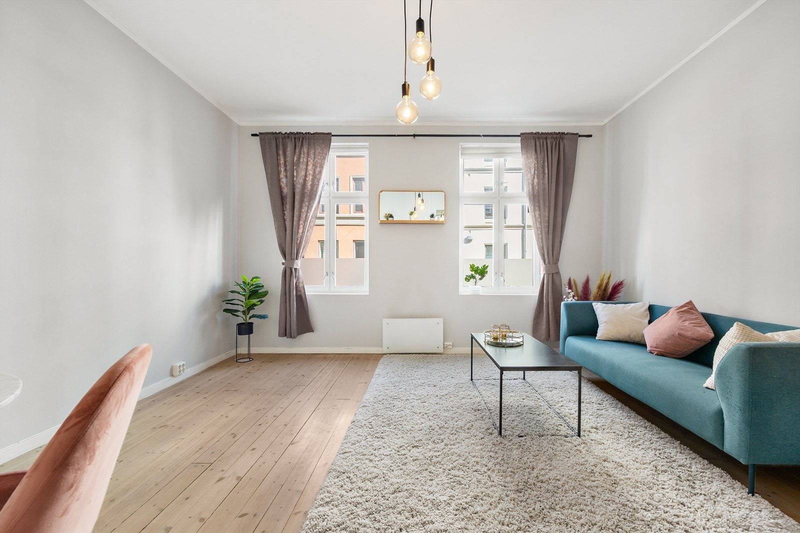 Lys stue med store vinduer og nøytral fargepalett. Galleribilde