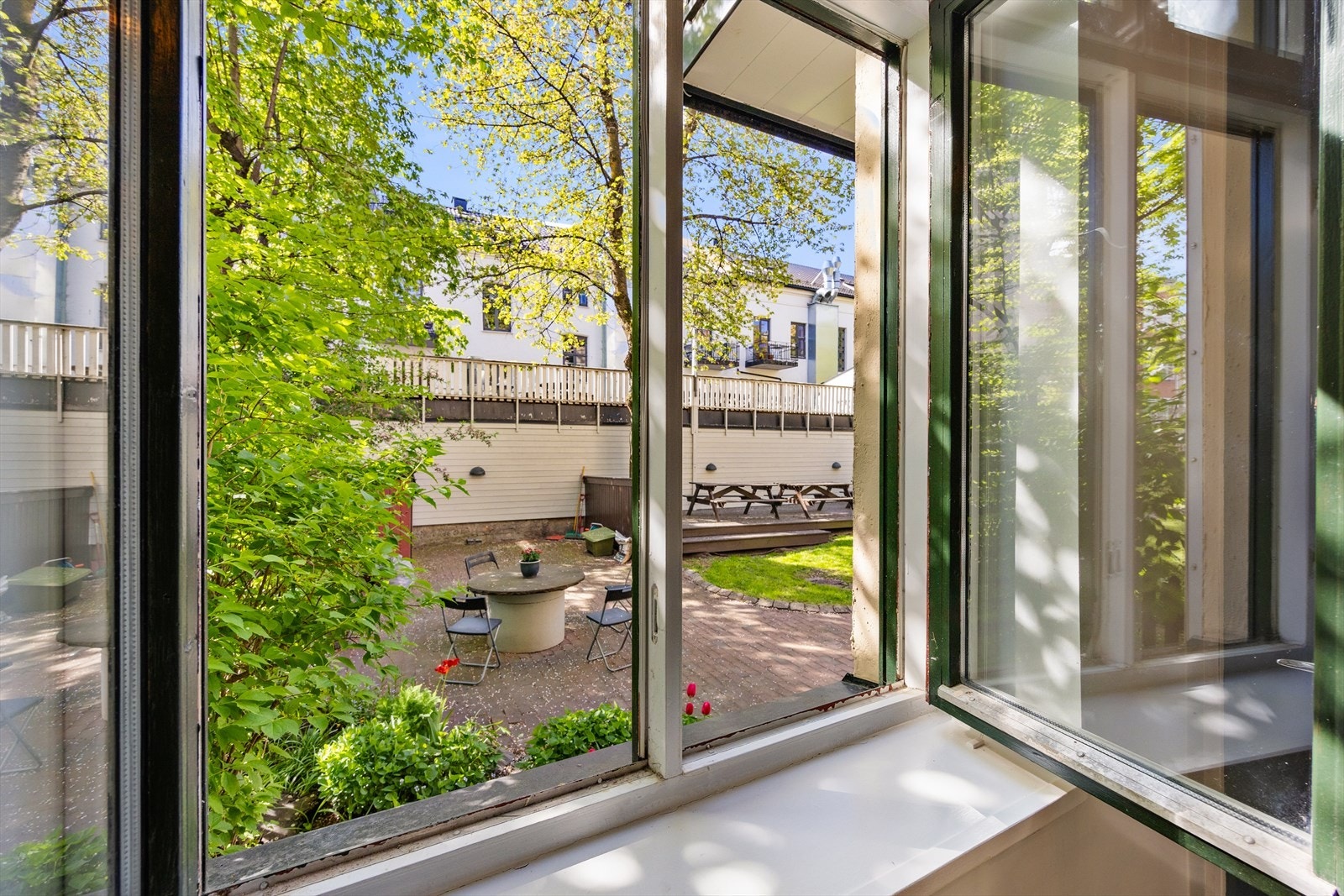 Koselig bakgård med sitteplasser og grønne omgivelser. Galleribilde