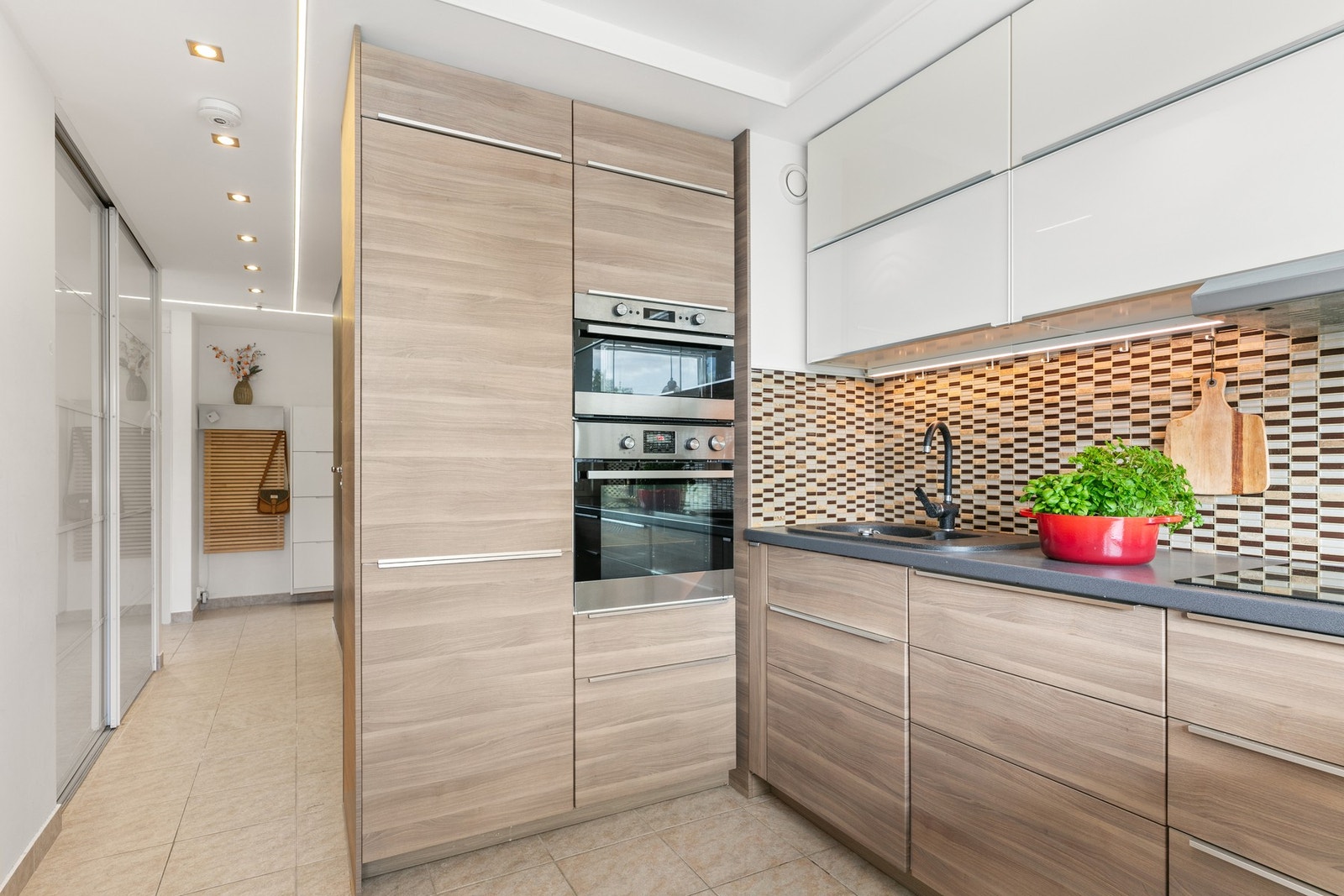 Entré/gang har åpen adkomst til et kjøkken med god lagringsplass og utgang til ballkong Galleribilde