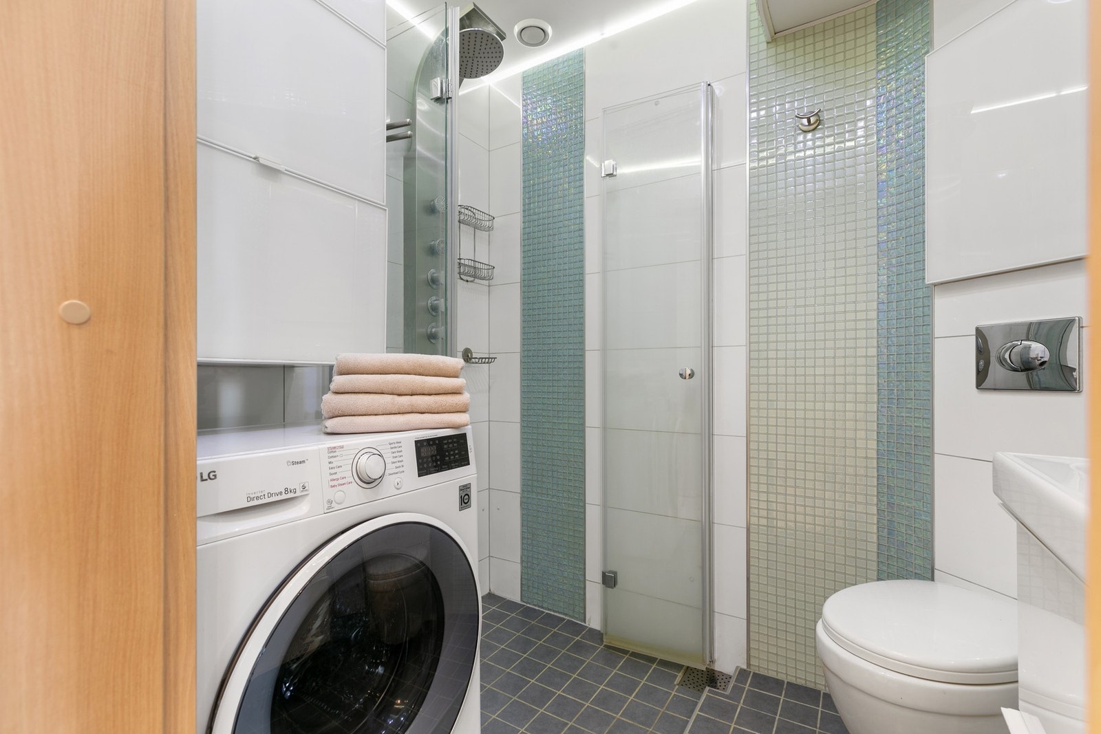 Vegger og gulv er flislagt, badet har elektriske varmekabler i gulv og opplegg for vaskemaskin Galleribilde