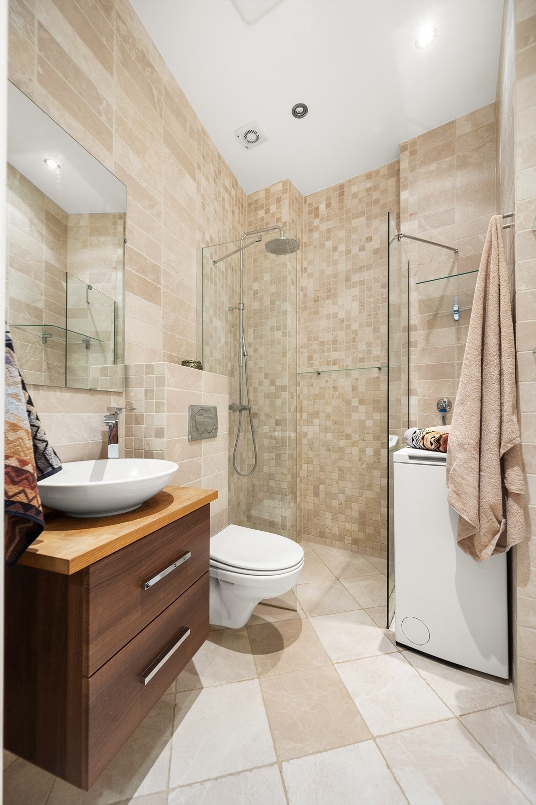 Baderomsinnredningen består av vegghengt toalett, servantskap, speil og dusjhjørne med glassfelt. Det er opplegg for vaskemaskin og behagelig gulvvarme. Galleribilde