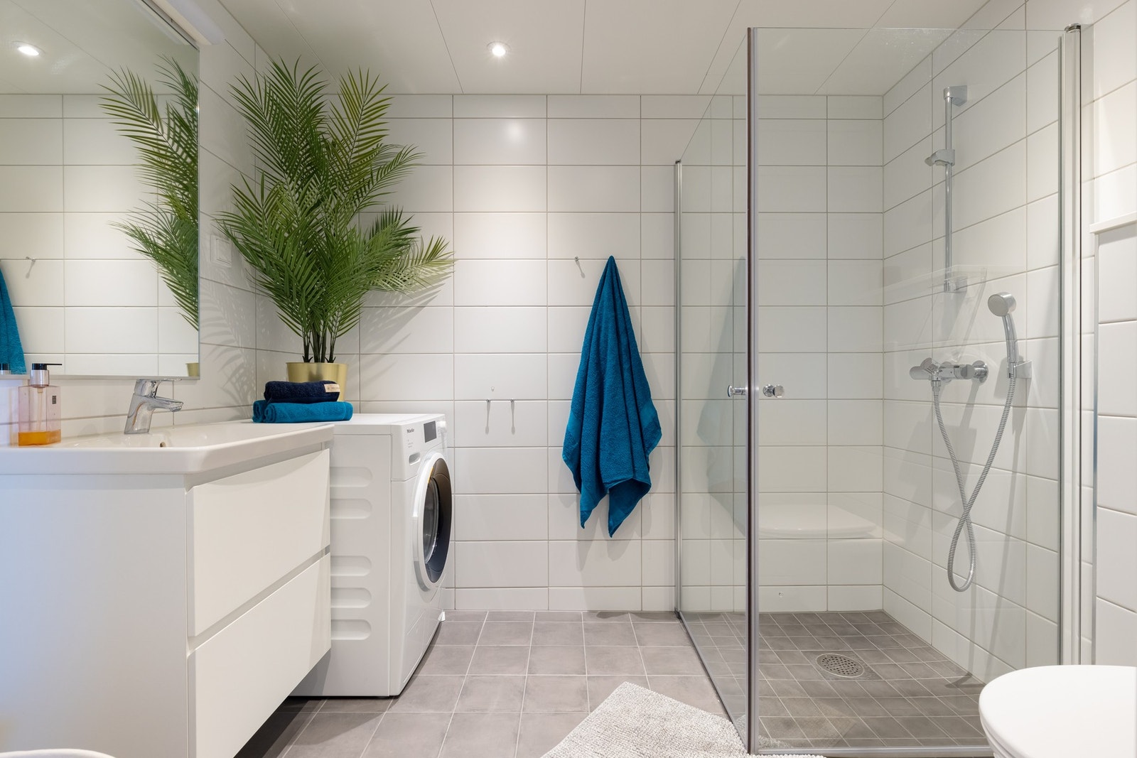 Videre er det vegghengt toalett og dusjhjørne med innfellbare glassdører som frigjør plass på gulvet. Badet har opplegg for vaskemaskin. Galleribilde