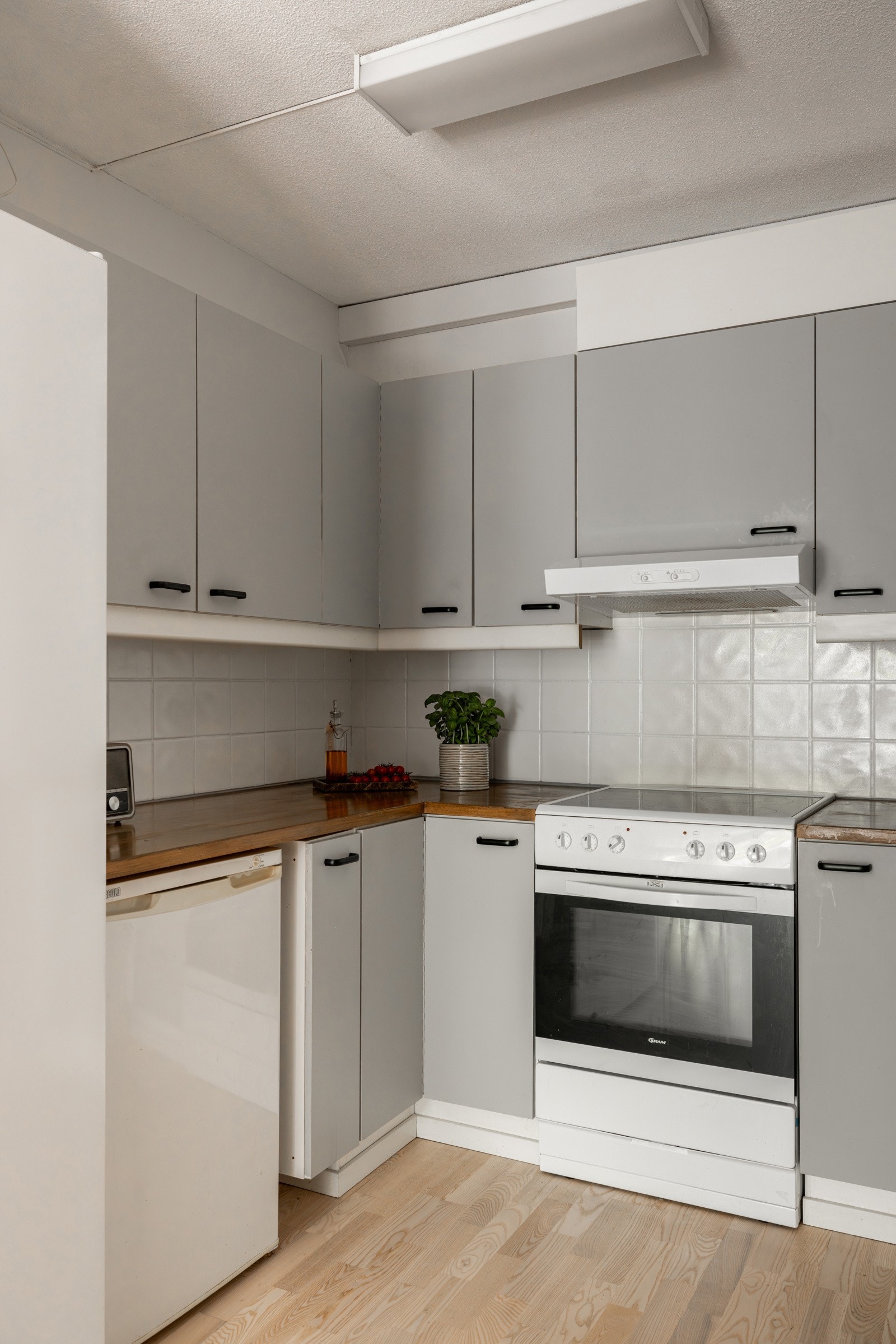 Det er fliser over benkeplate av tre, nedfelt oppvaskkum med ett-greps kjøkkenarmatur, i tillegg til benekeskapsbelysning og stikkontakter over kjøkkenbenk. Galleribilde