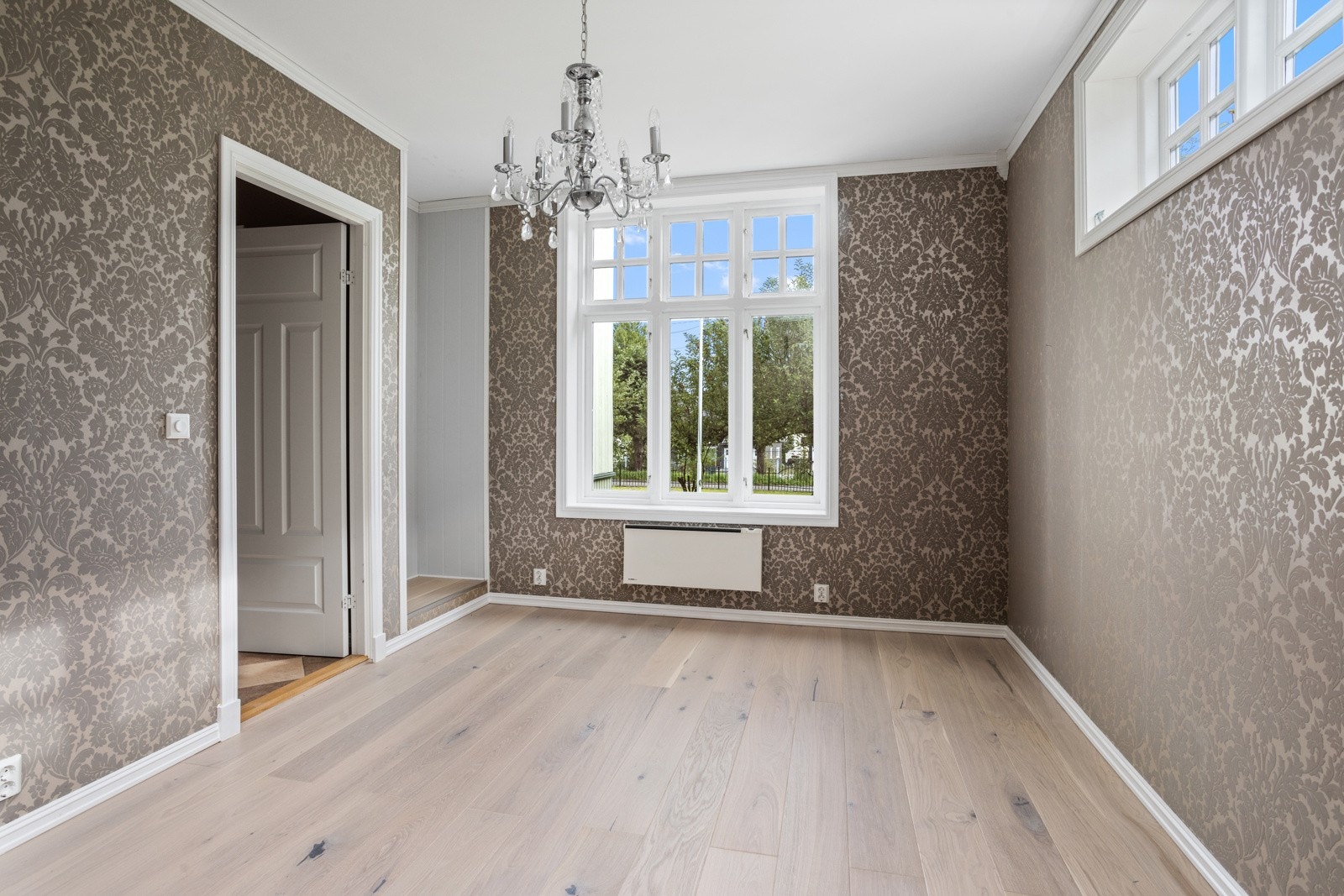 Soverom med rikelig lysinnslipp, plass til soveromsmøblement og tapet på vegger Galleribilde