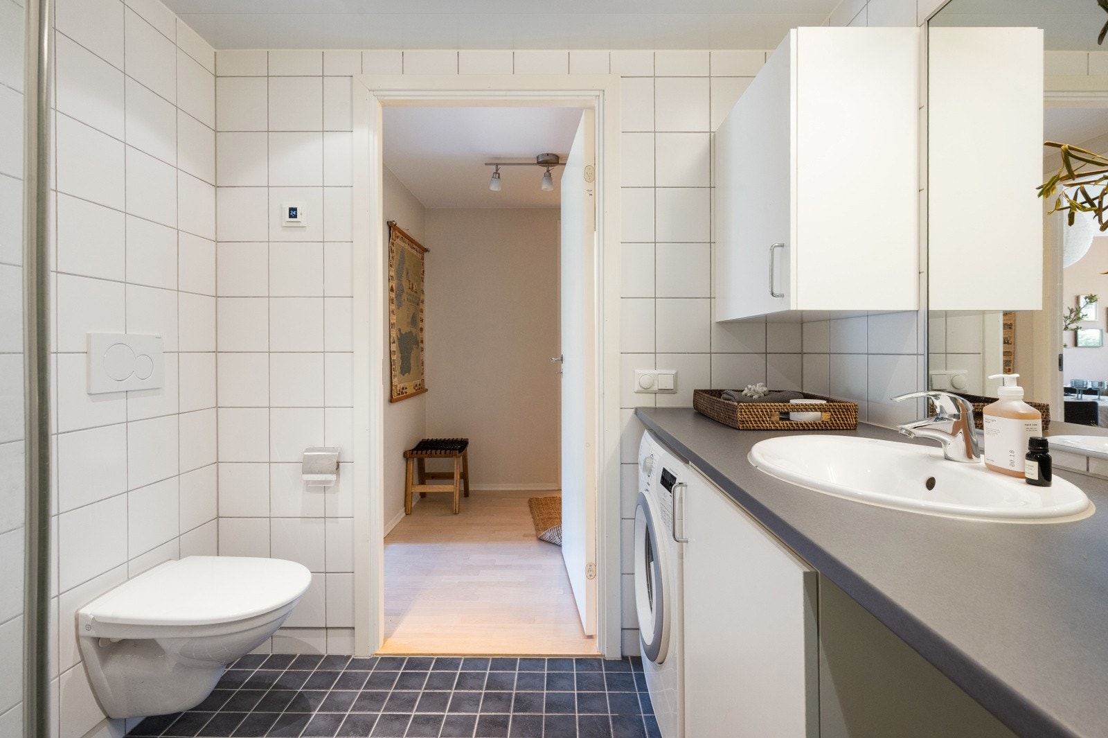 Rommet er helfliset med mørke gulvfliser og lyse veggfliser, som gir et rent og tidløst uttrykk. Galleribilde