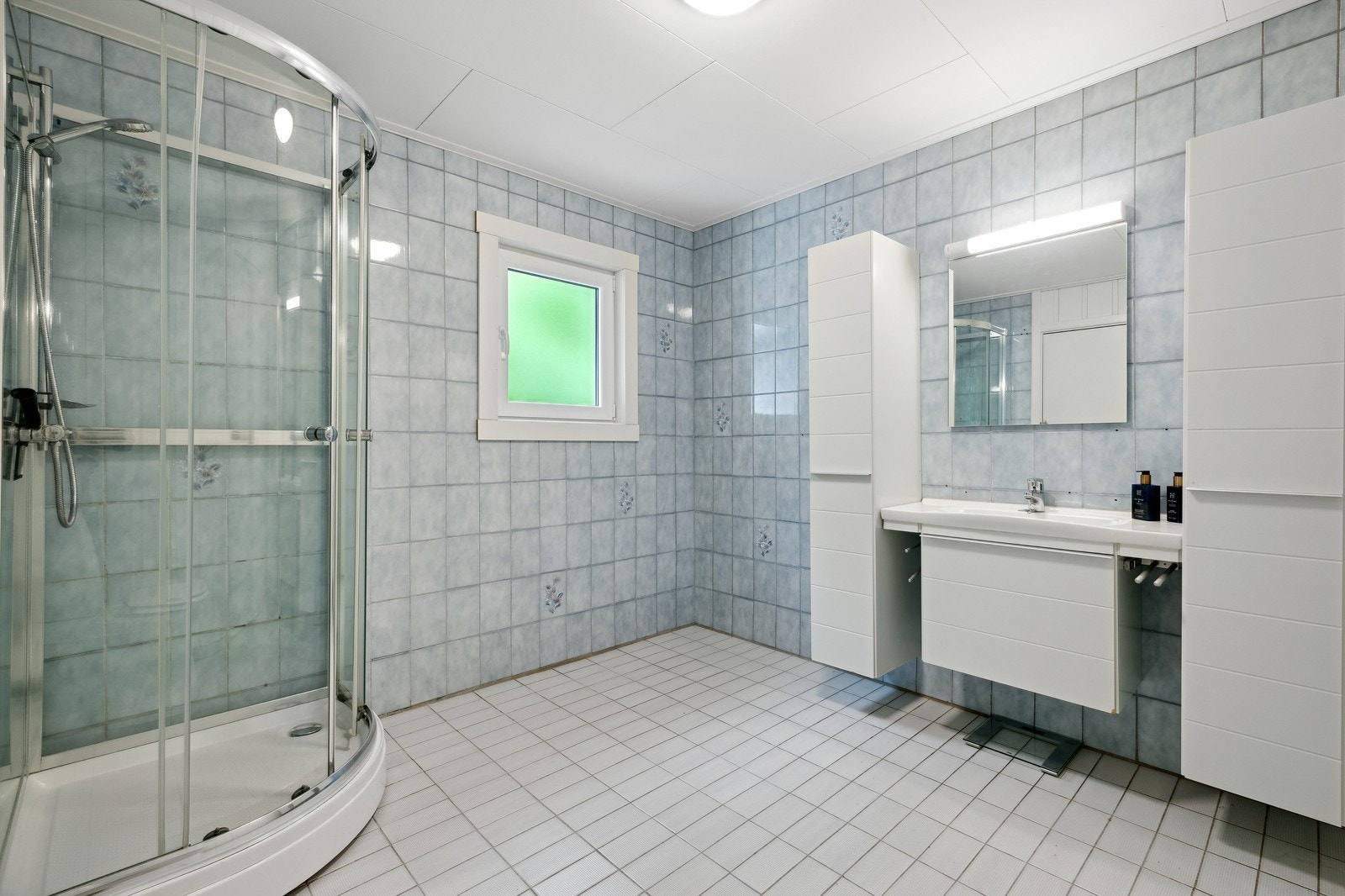 Stort bad med dusj, toalett og servant. Det er varmekabel i gulvet. Galleribilde