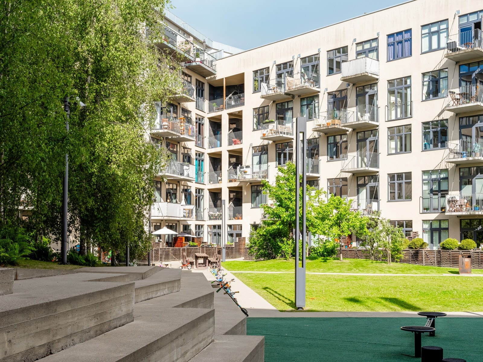 Bakgården er nøye opparbeidet, med sykkelparkering, lekeplass og hyggelige sittegrupper som innbyr til både avslapning og fellesskap. Galleribilde