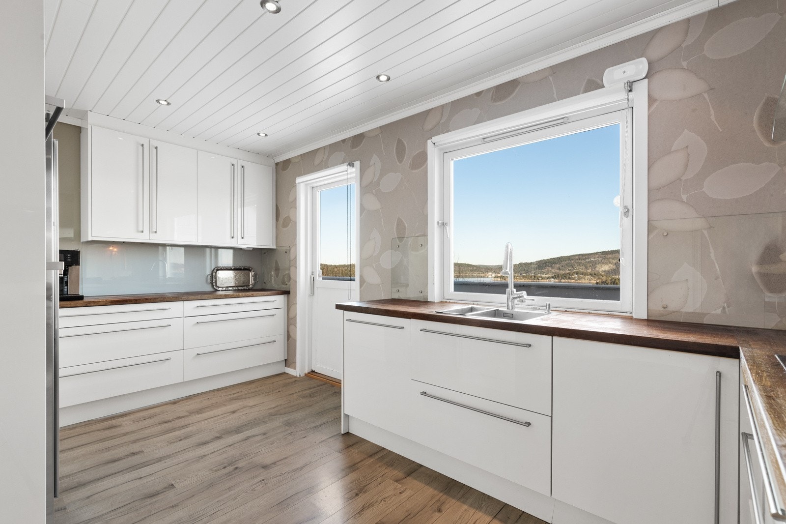 Det er utgang til den nordvest-vendte verandaen på 74 kvm som strekker seg rundt hushjørnet fra kjøkkenet. Galleribilde