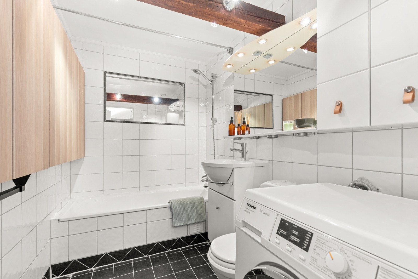 Lyst flislagt baderom med behagelig varme i gulv. Opplegg for vaskemaskin. Galleribilde