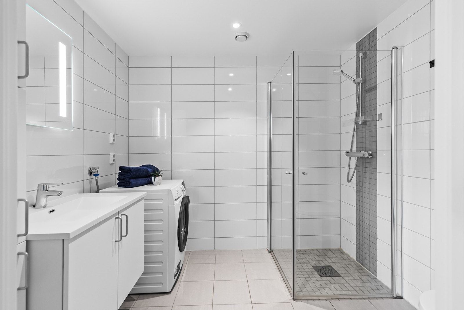 Badet er utstyrt med gulvvarme, servant m/lagring, vegghengt toalett og dusjhjørne Galleribilde