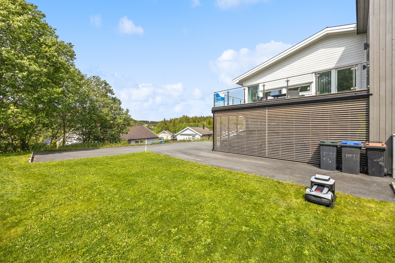 Asfaltert gårdsplass med kantstein mot plen gir et godt førsteinntrykk av eiendommen. Galleribilde