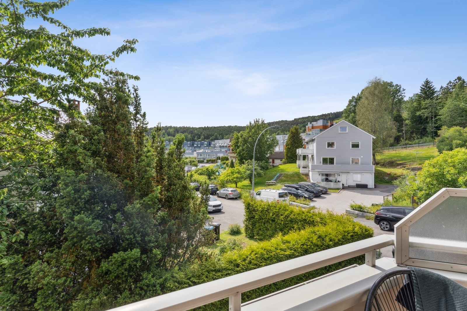 Boligen er omkranset av frodige grøntarealer, med sittegrupper og lekestativ for barna. Galleribilde