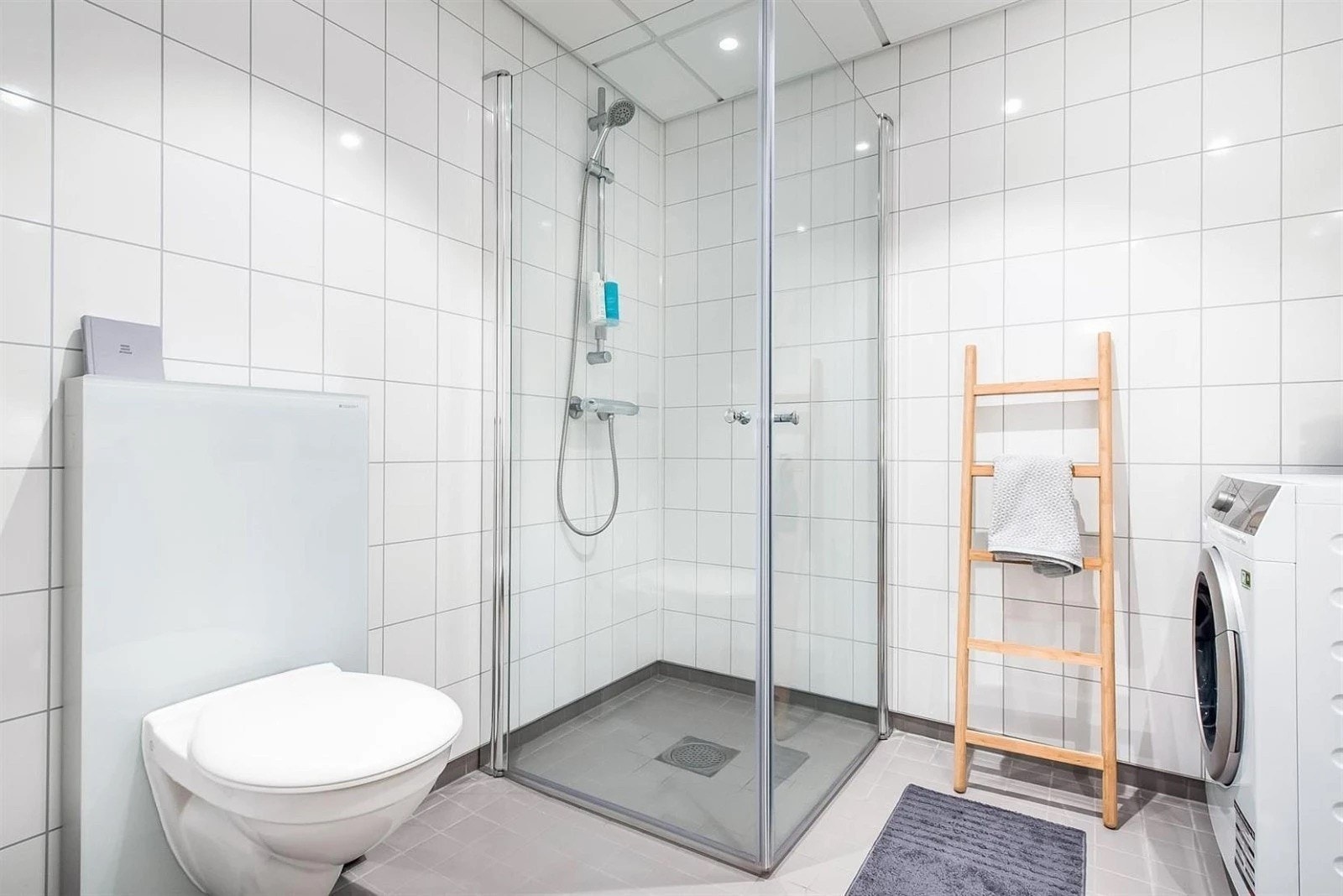 Leiligheten har et lyst og moderne baderom fra byggeåret 2016. Baderommet har grå fliser på gulv med gulvvarme, hvite fliser på veggene, downlights i himlingen og avtrekk via balansert ventilasjon. Galleribilde