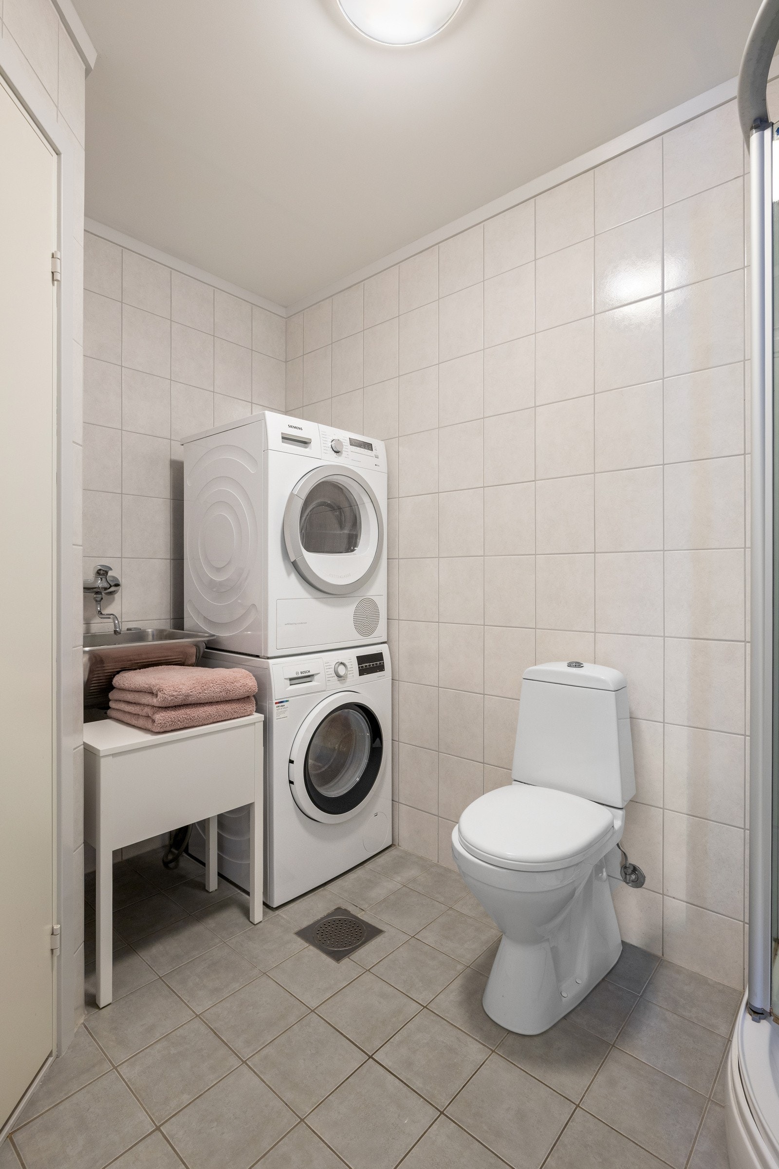 Videre er badet utstyrt med dusjkabinett, frittstående toalett og opplegg for vaskesøyle. Galleribilde