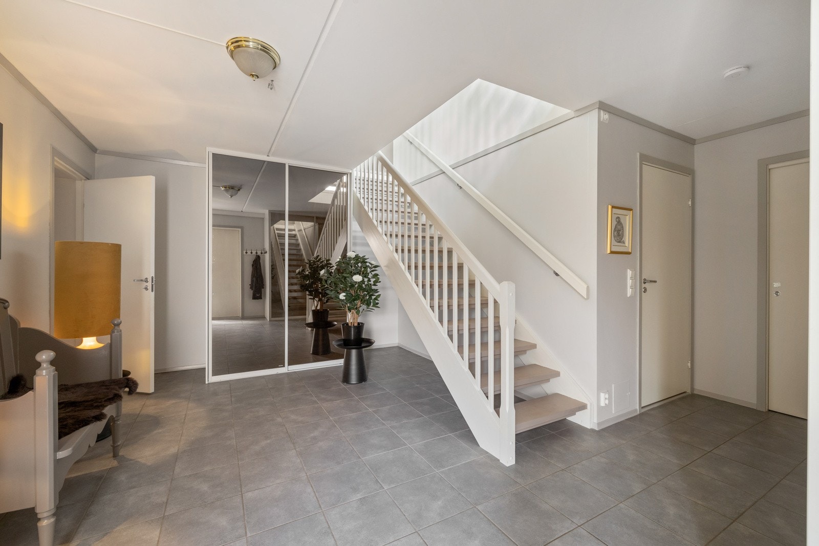 Entreen har grå gulvfliser med vannbåren varme, gråmalte vegger og beiset trapp med åpne trinn til neste etasje. Galleribilde