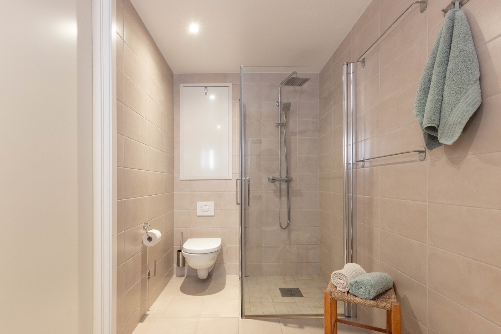 Innredet med servant med slette skuffer, speil med belysning, dusjhjørne med regndusj og vegghengt toalett. Galleribilde