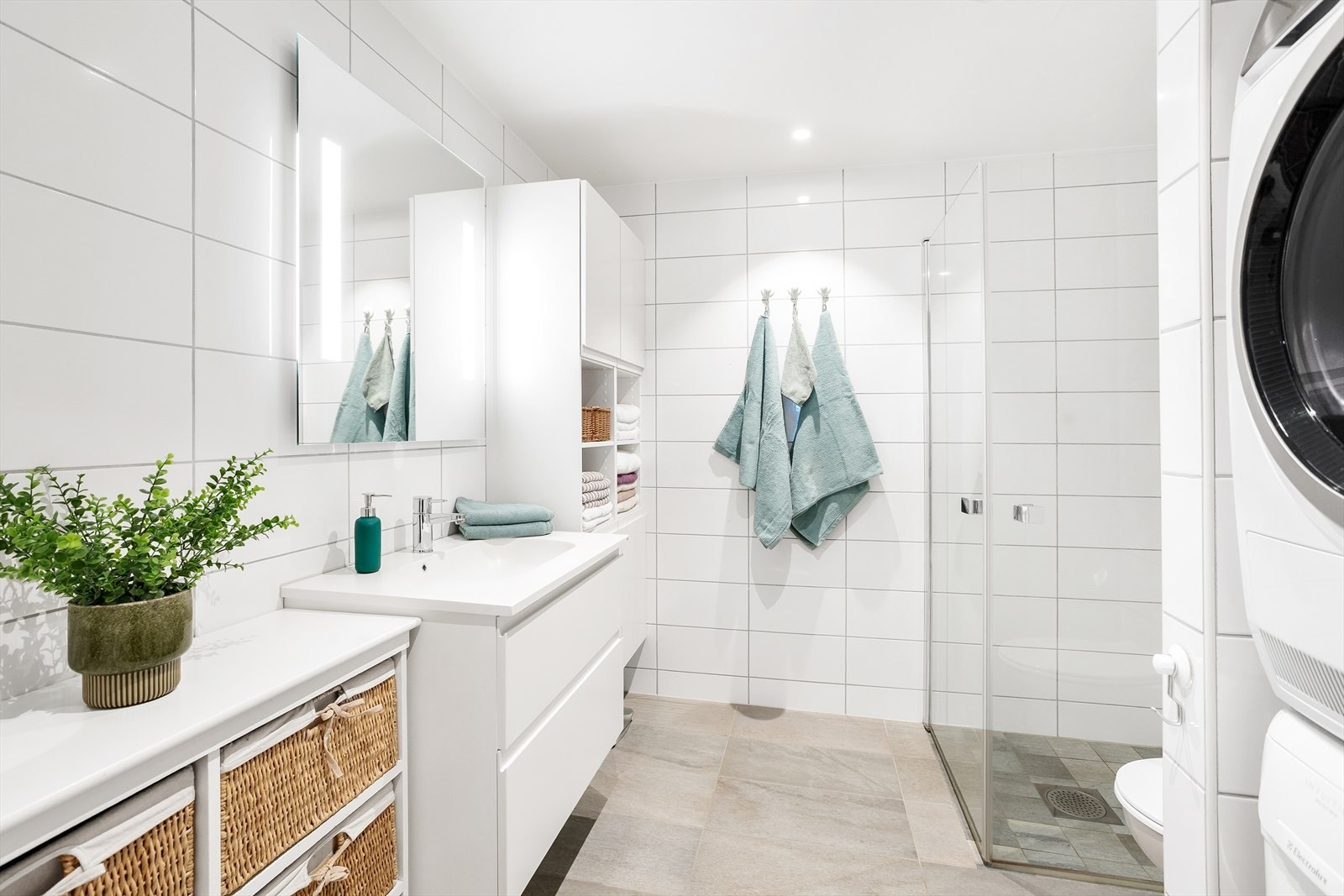 Stilrent og moderne bad med lyse fliser, varmekabler i gulv og en utstrakt bruk av downlights i himling. Galleribilde