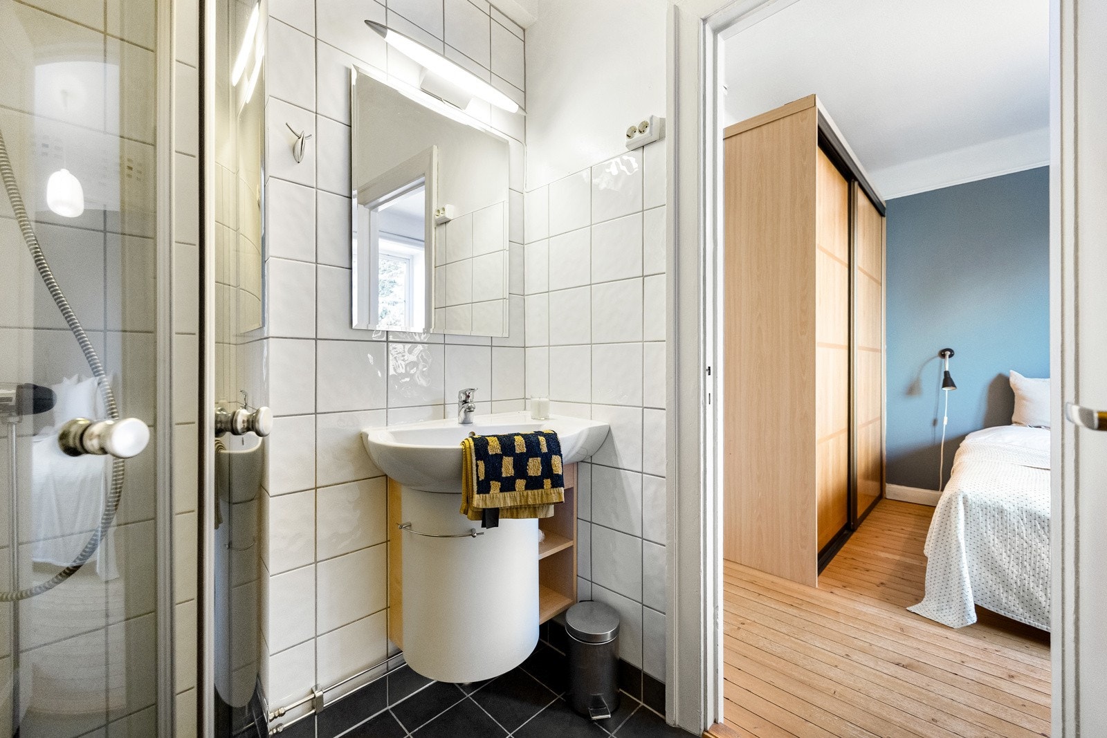 Badet er praktisk innredet med dusjhjørne, veggmontert servantskap og vannbåren håndkletørker som gir både varme og en luksusfølelse. Galleribilde