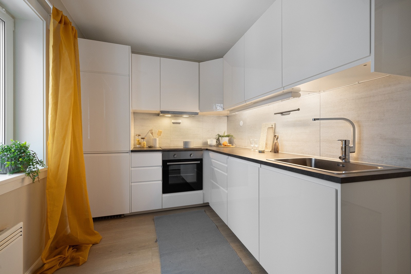 Armatur, laminat benkeplate med nedfelt stålkum og keramisk topp, integrert komfyr, oppvaskmaskin og kjøl/frys. Galleribilde