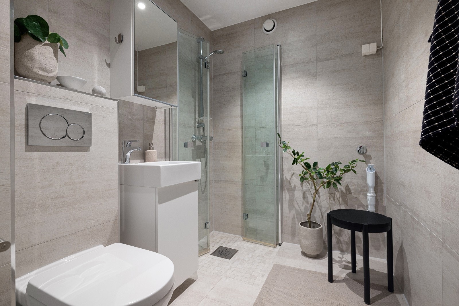 Flislagt bad/wc med varmekabler, avtrekk, speilskap, armatur, downlights og opplegg for vaskemaskin. Galleribilde