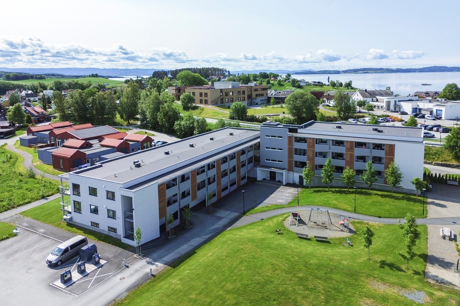 Pent opparbeidet fellesområde med asfalterte veier, plenlagt areal, lekestativ og benker. Galleribilde