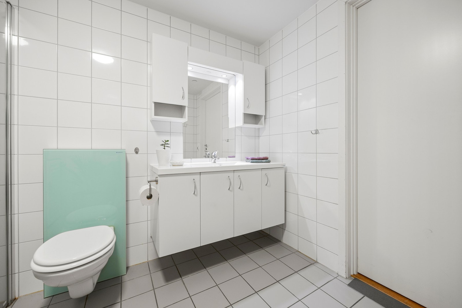 Badet er utstyrt med servantskap, vegghengt toalett og dusj, samt opplegg for vaskemaskin Galleribilde